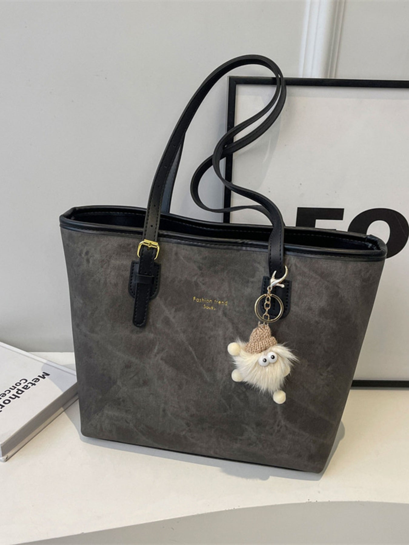 Distressed dark gray pu leather tote bag with buckle accents and a fuzzy charm.