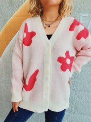 Blush pink acrylic cardigan with playful red floral appliques, V-neck, button front, and ribbed trim.