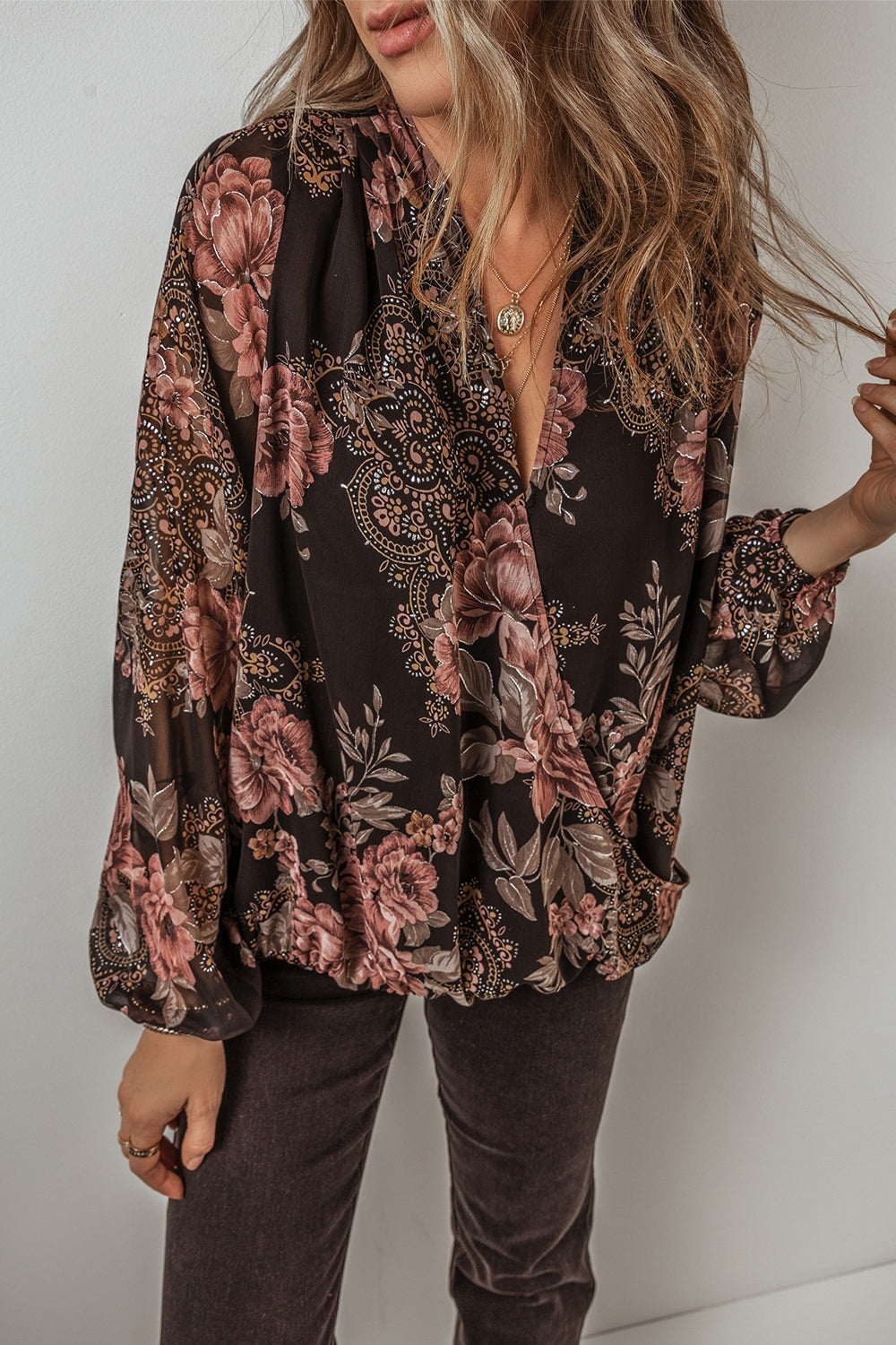 Black floral print surplice blouse with blouson sleeves and a deep V-neck.