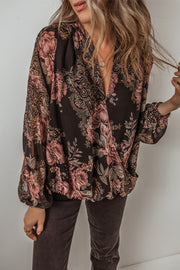 Black floral print surplice blouse with blouson sleeves and a deep V-neck.
