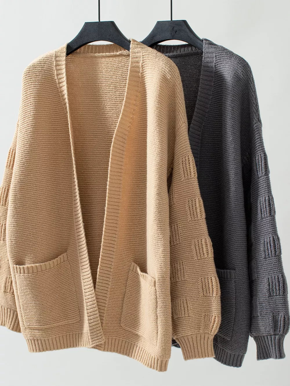 Chunky knit open-front cardigan in camel and dark gray with pockets and textured sleeves.