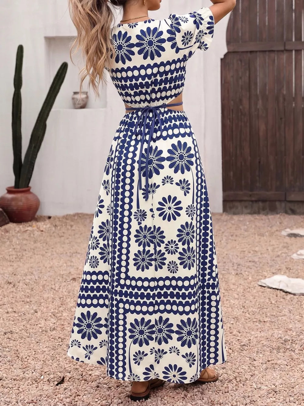 Maxi dress with blue floral print, cutout waist, tie detail, and short sleeves.