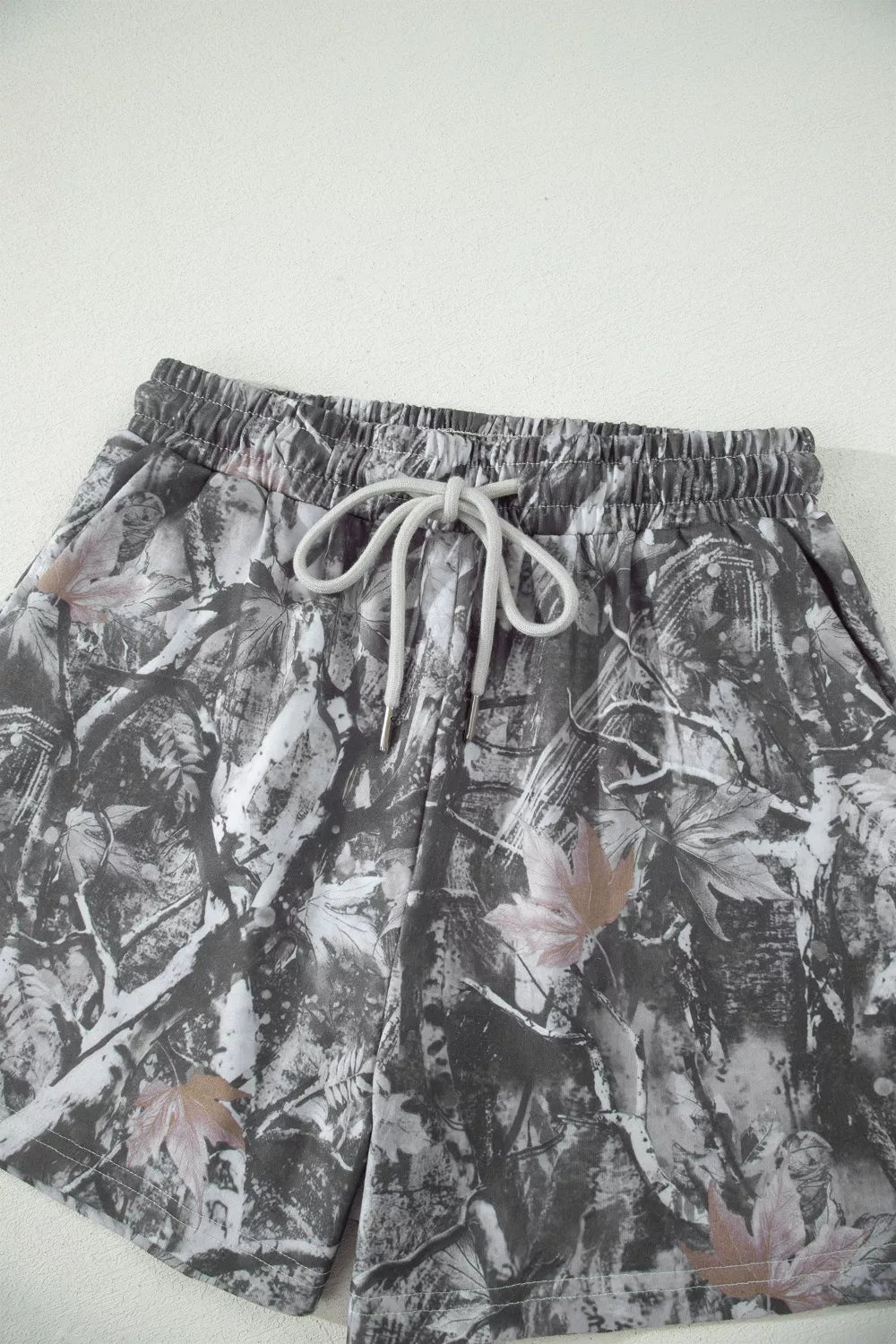 Maple leaf print elastic waist shorts with drawstring in abstract camouflage pattern.