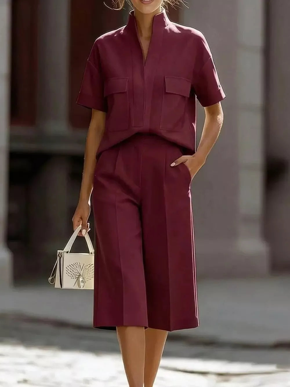 Burgundy two-piece set with pocketed shirt and culottes, styled with a white handbag.