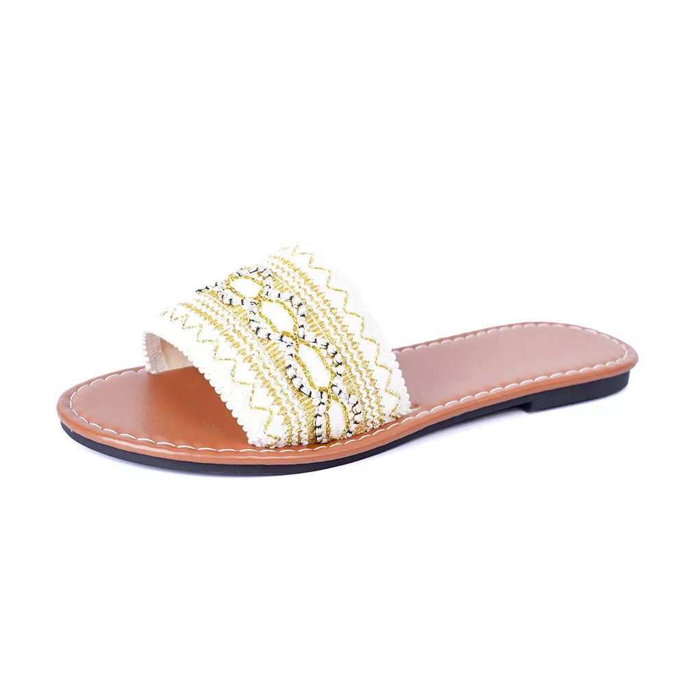 White embroidered artisan open-toe slide sandals with gold detailing and a brown sole.
