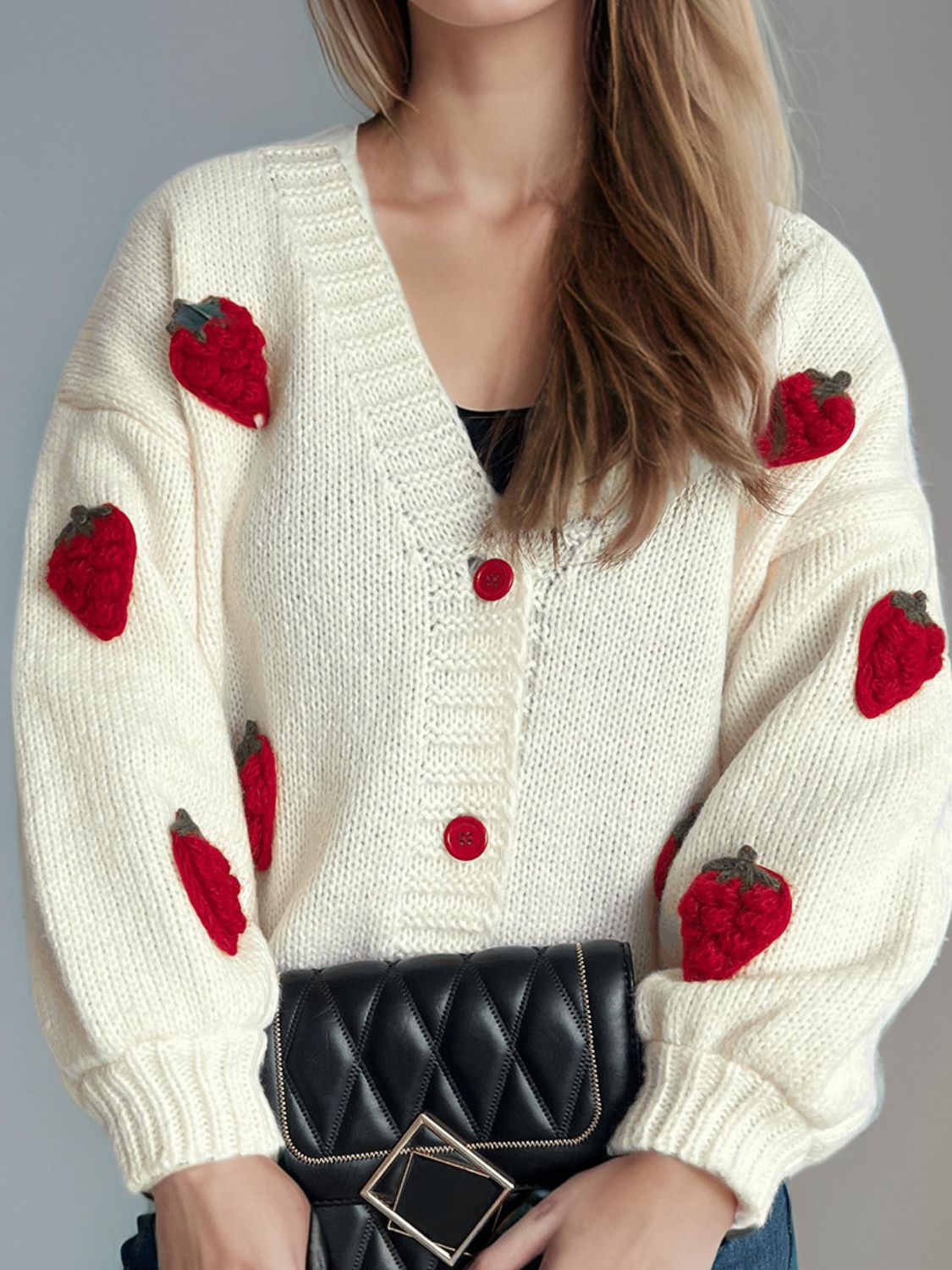 Cream knit cardigan with red strawberry appliqués and red buttons.