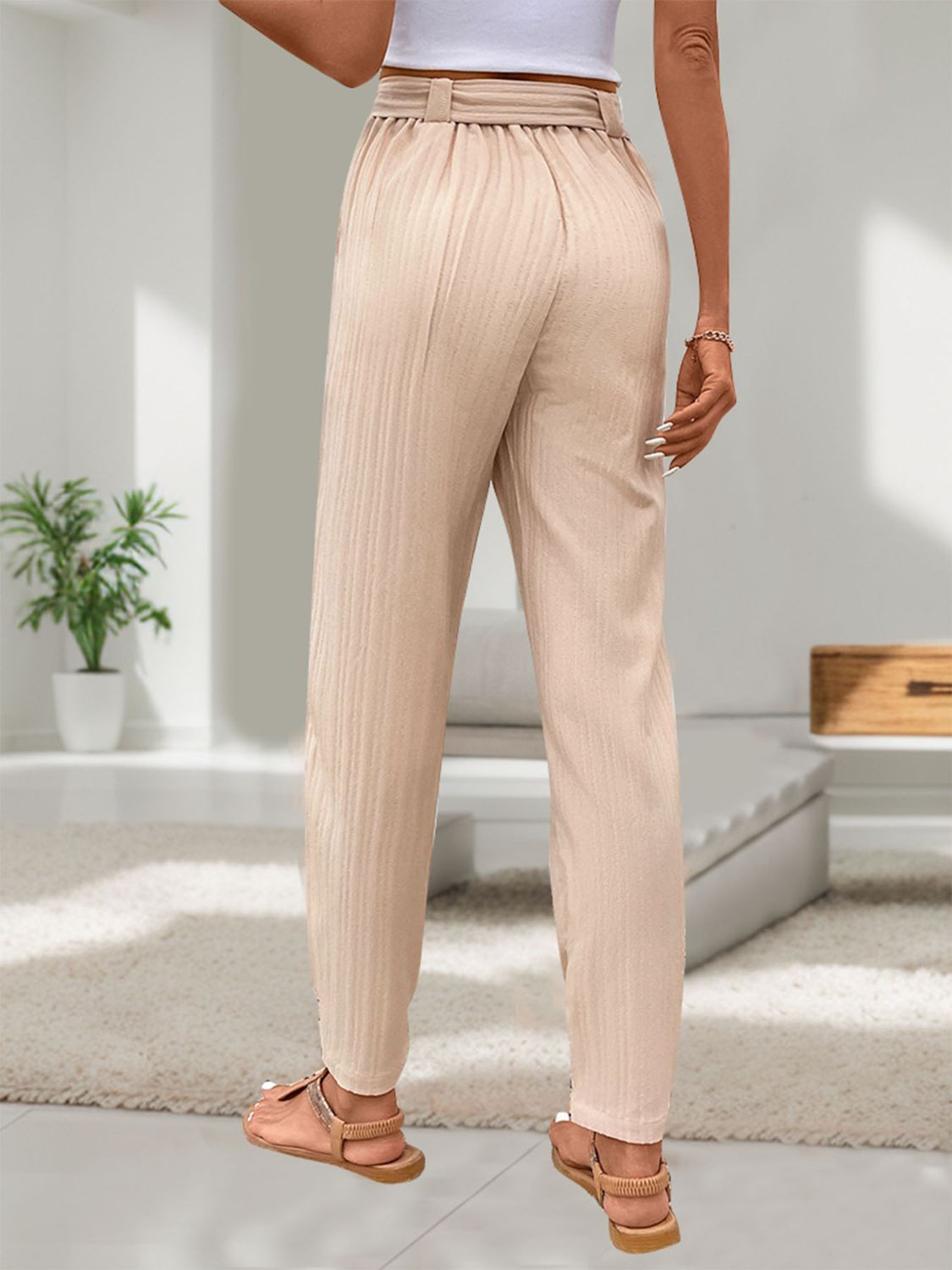 Tan textured linen paperbag trousers with cuffed ankles and a belted waist.