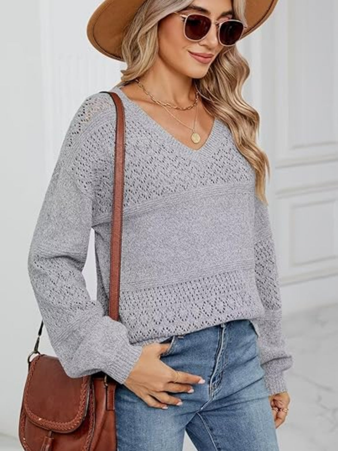 Light gray eyelet stitch V-neck pullover sweater with textured panels and long sleeves.