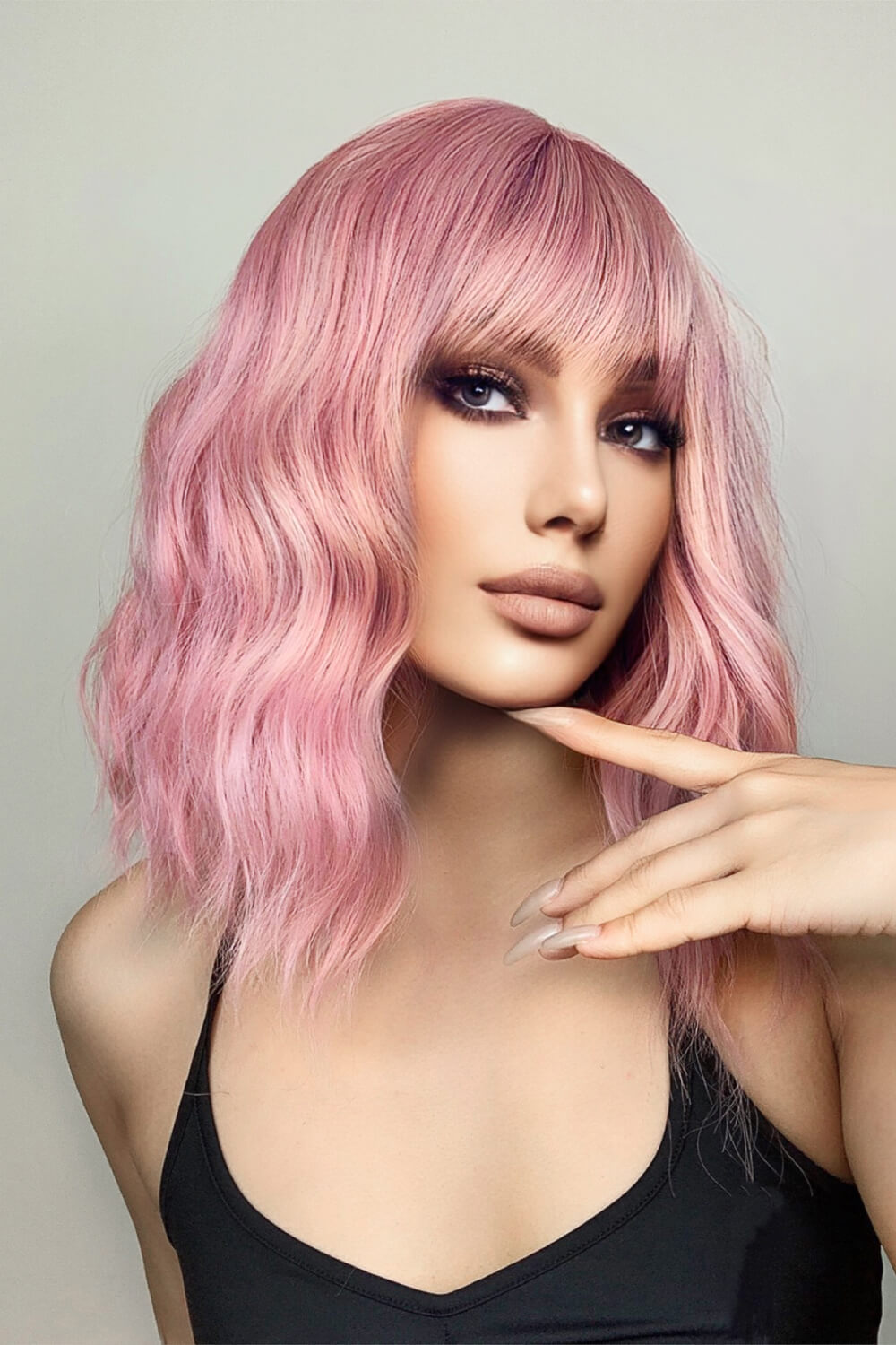 Pink bob wig with bangs and loose waves, styled casually.