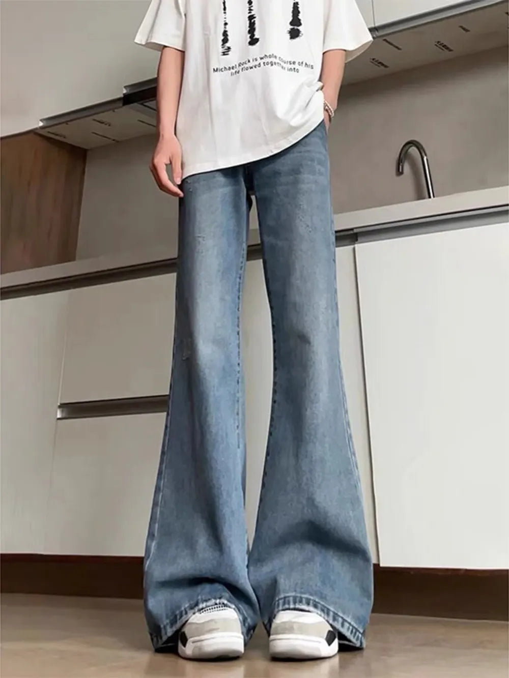 Men's light wash denim flare leg jeans with distressed details.