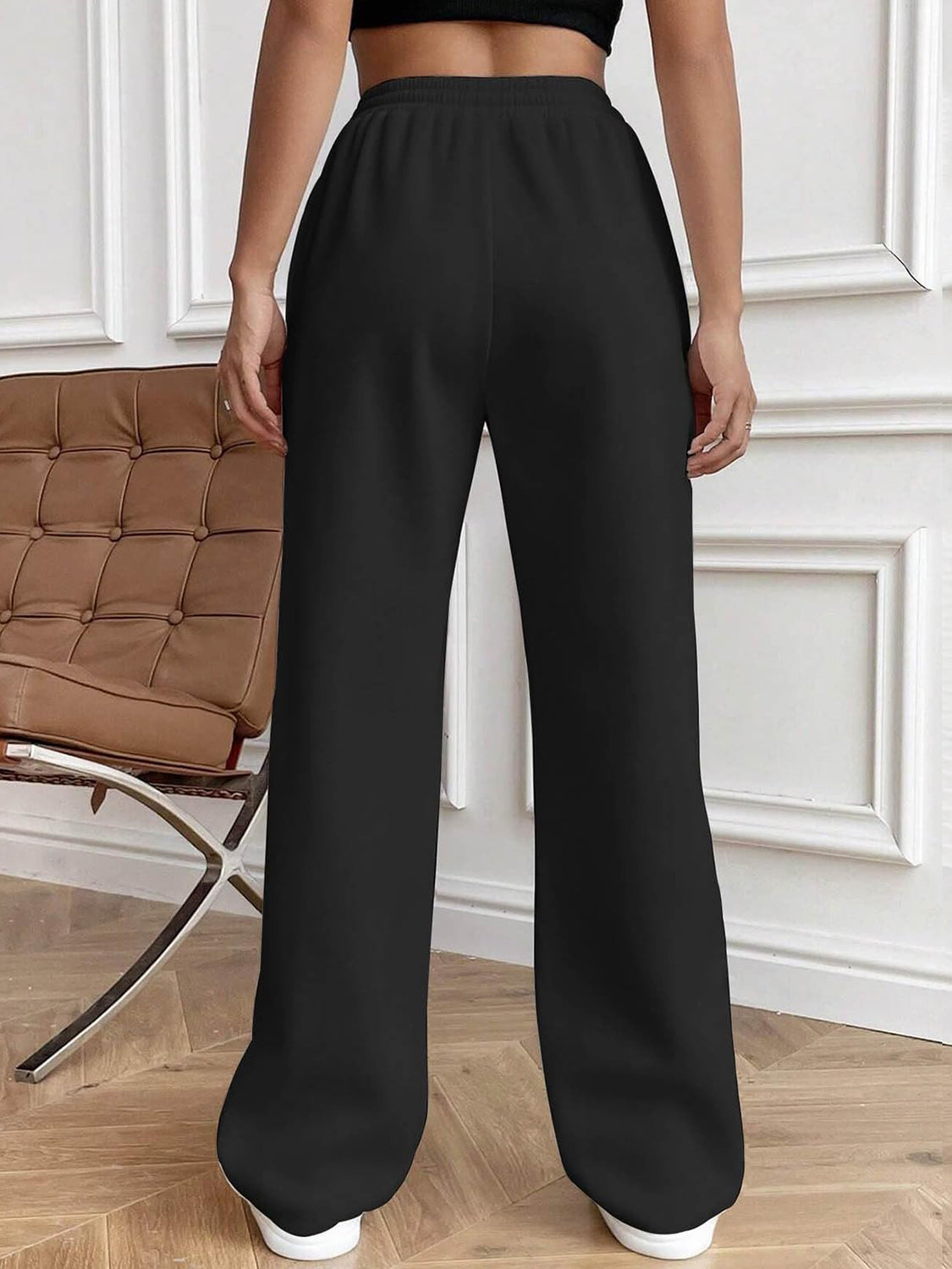 Black pleated palazzo trousers with drawstring waist and wide legs.