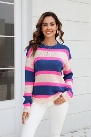 Crewneck knit sweater with bold horizontal stripes in dark blue, pink, and cream.