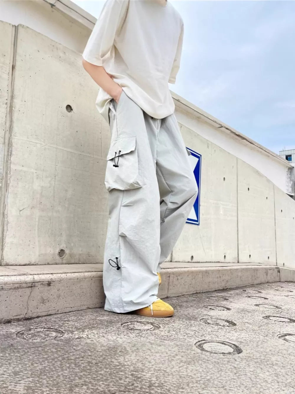 Grey cargo sweatpants with adjustable drawstring details and multiple pockets.