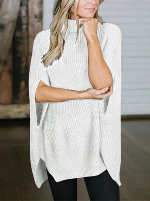 White acrylic turtleneck sweater with cape sleeves and side slits.