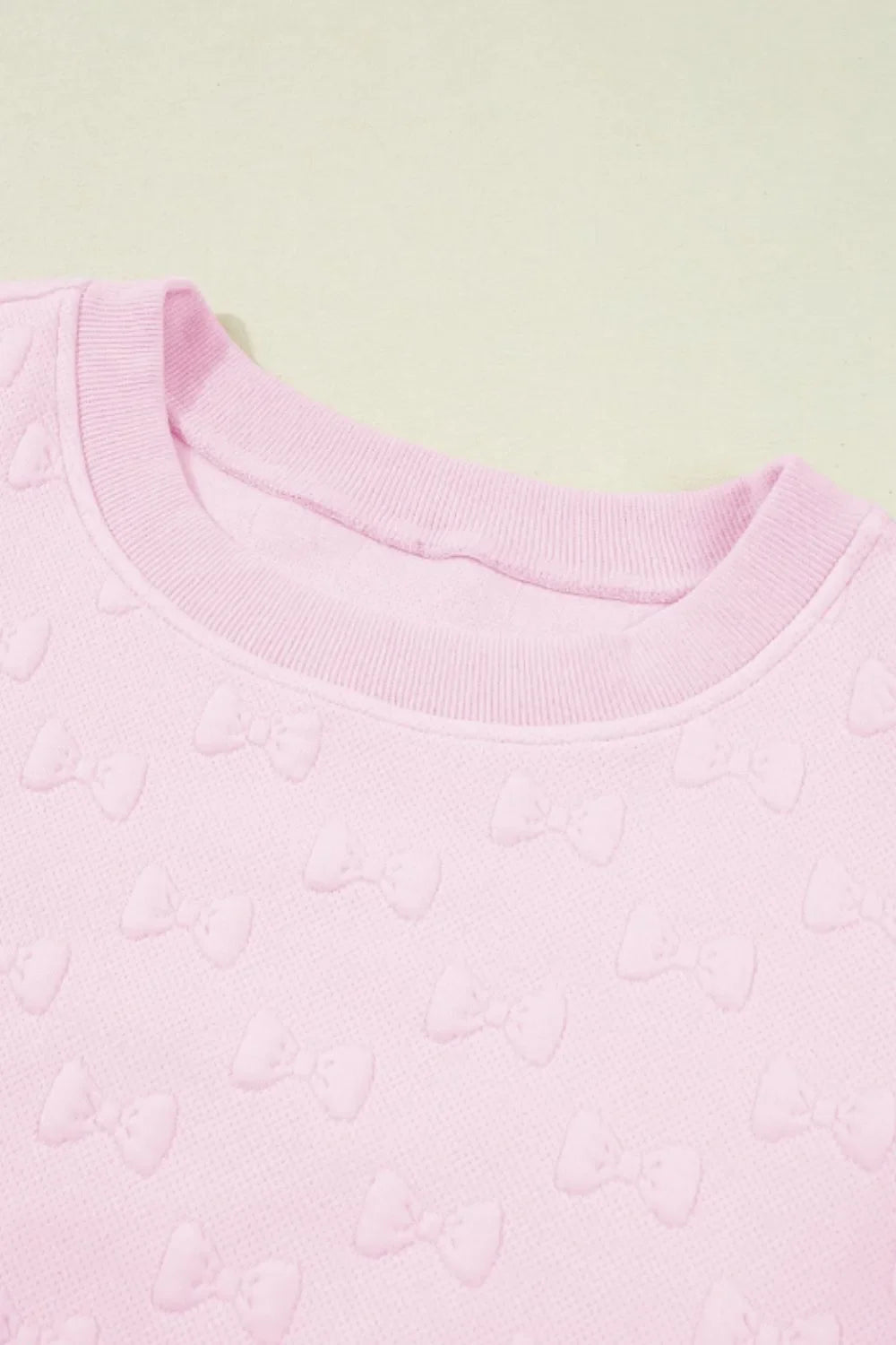 Blush pink loungewear set with embossed bow pattern and crew neck.