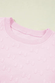 Blush pink loungewear set with embossed bow pattern and crew neck.