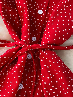 Red polka dot maxi dress with white buttons and a tie belt.