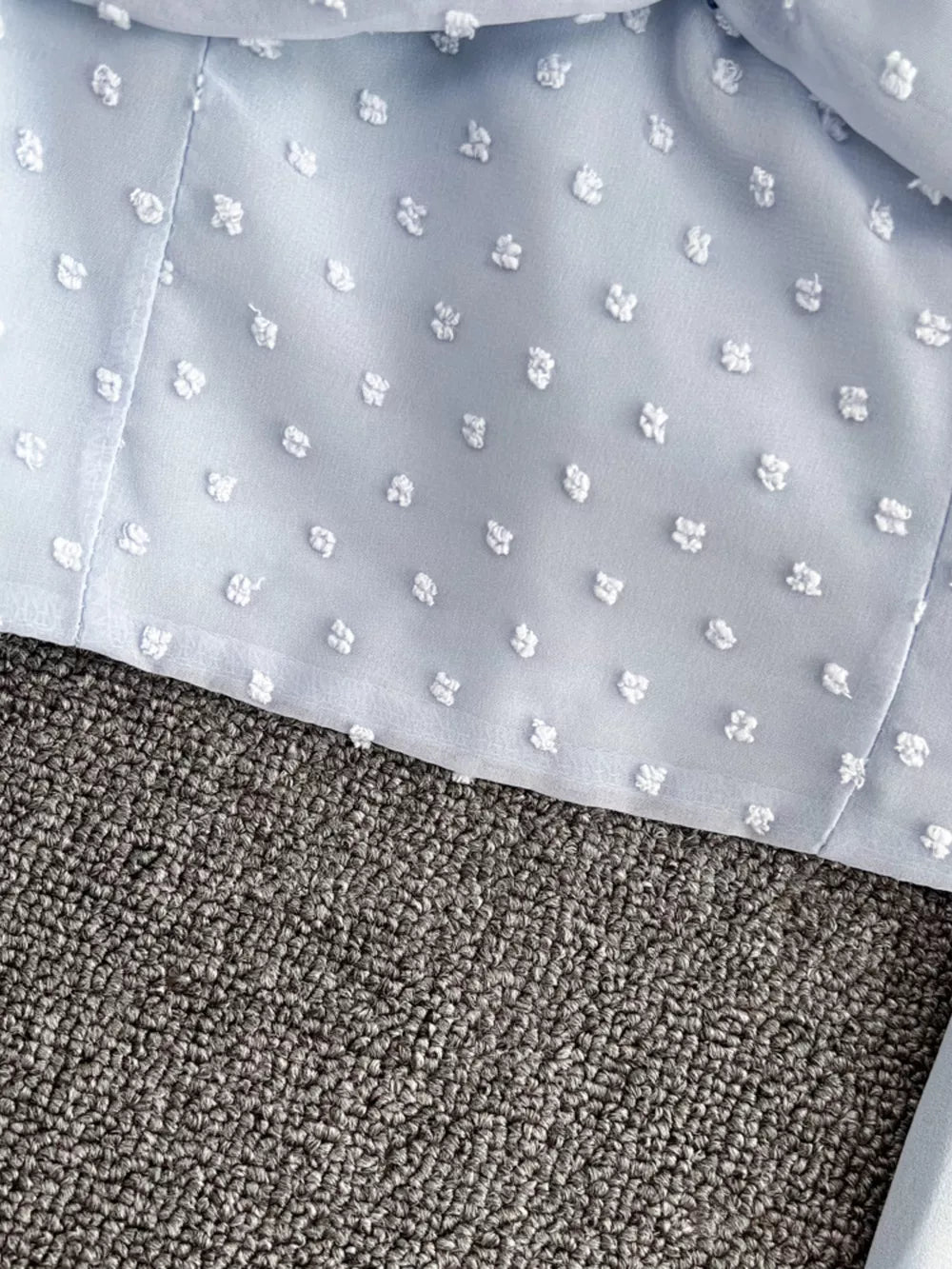 Blue Swiss dot maternity blouse with ruffled detail and sheer fabric.