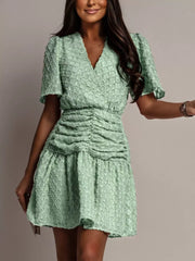 Textured light green ruched V-neck mini dress with short puff sleeves.