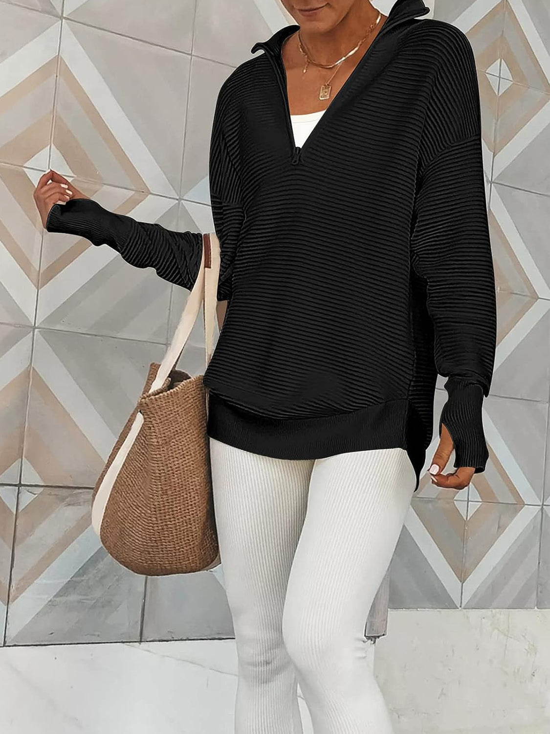 Black ribbed knit pullover with funnel neck and quarter zip, long sleeves with thumbholes.