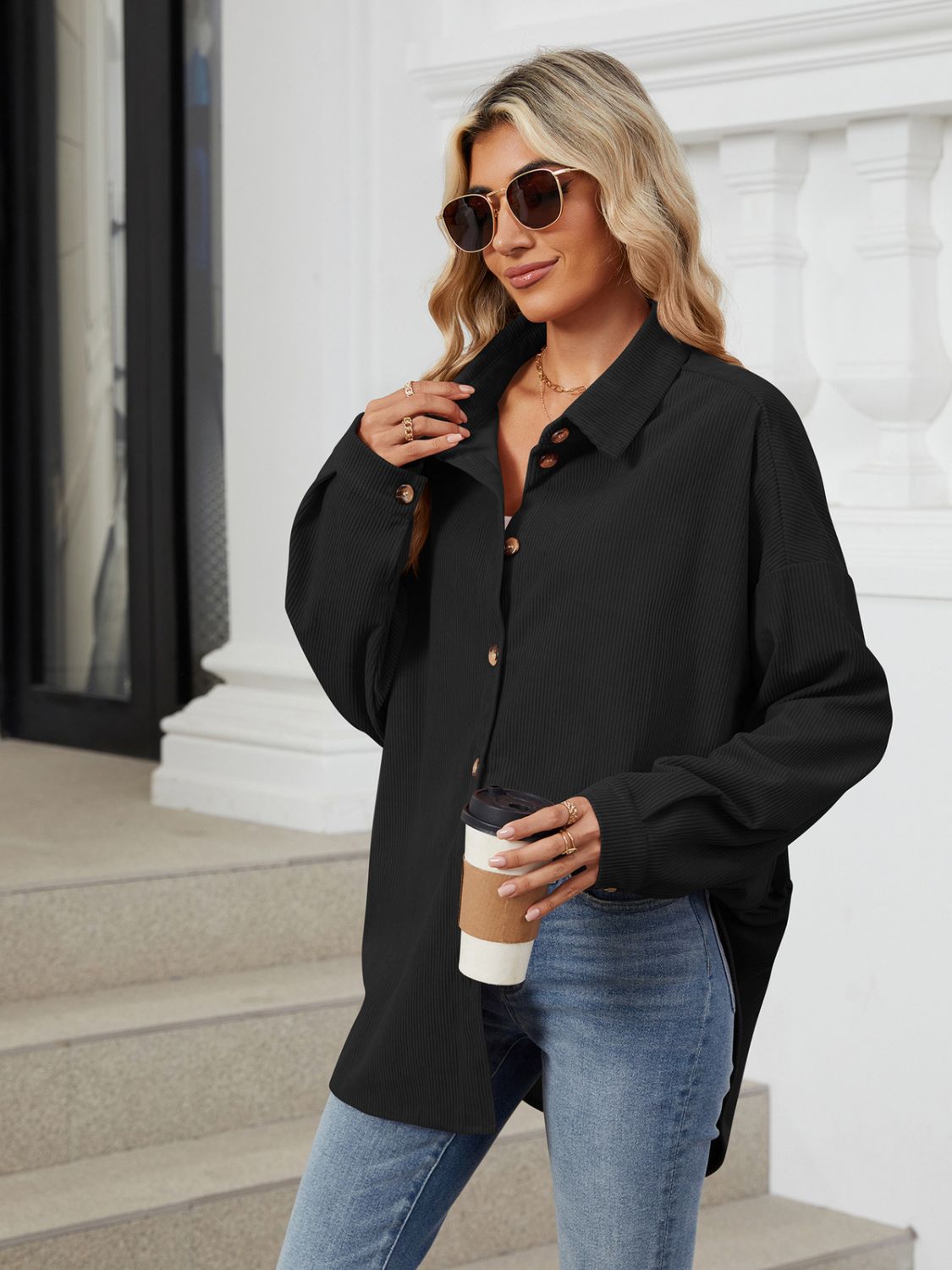 Black oversized corduroy shirt jacket with button front and collar, styled casually.