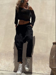 Black asymmetric crochet crop top with off-shoulder detail and long sleeves.
