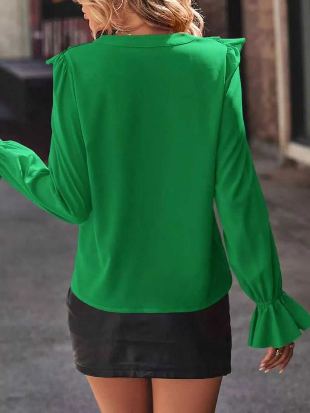Green blouse with cascading ruffle sleeves and button front detail.