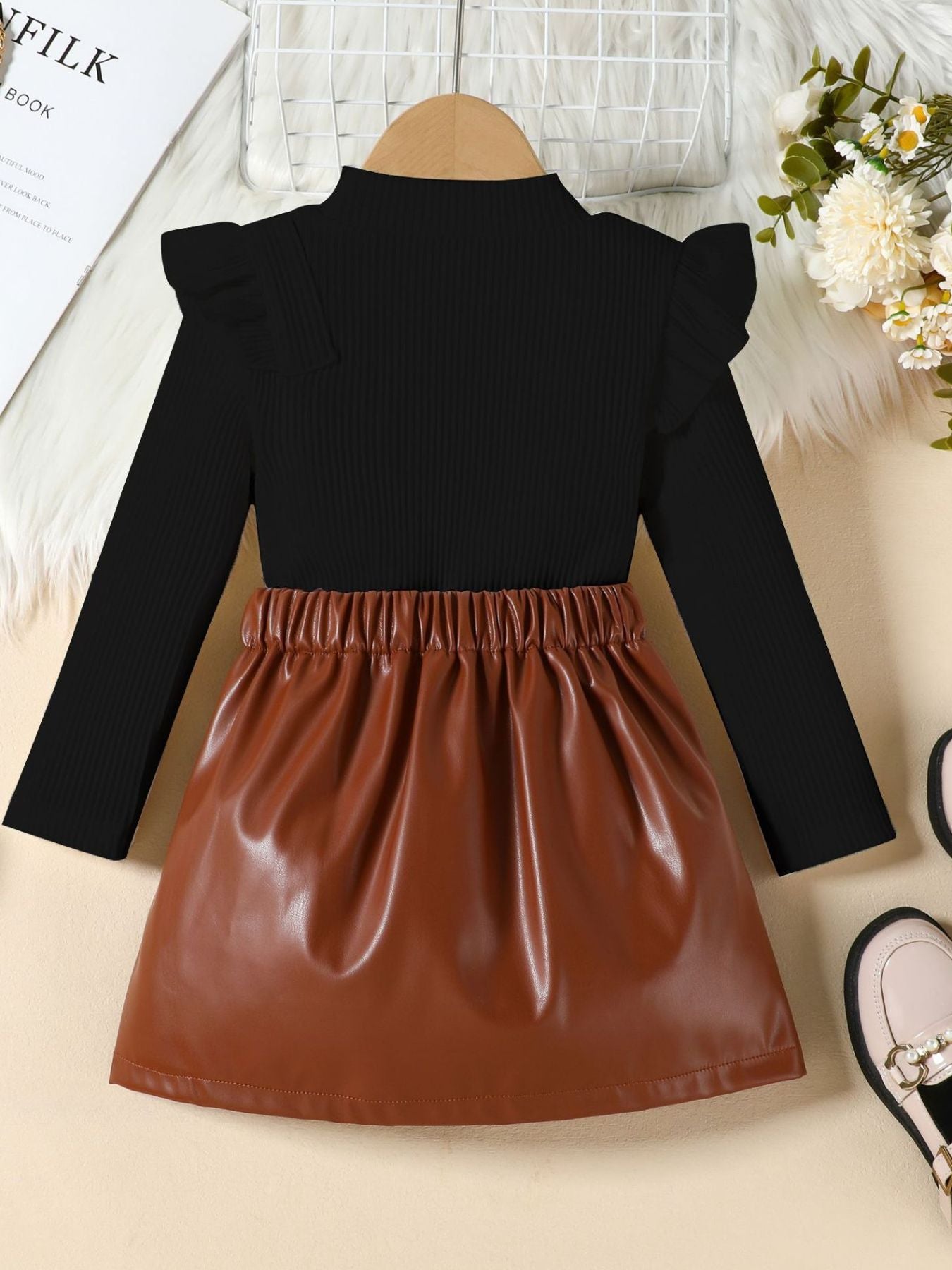 Black ribbed long sleeve top with ruffled shoulders and brown faux leather skirt.