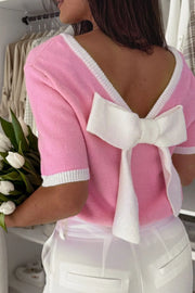 Pink knit top with white contrast trim and a large bow detail on the back.