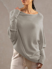 Light gray off-shoulder knit sweater with textured cuffs and draped fit.