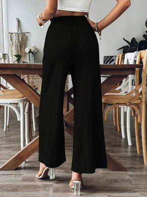 Black textured wide-leg palazzo trousers with a ruffled waist and a relaxed fit.