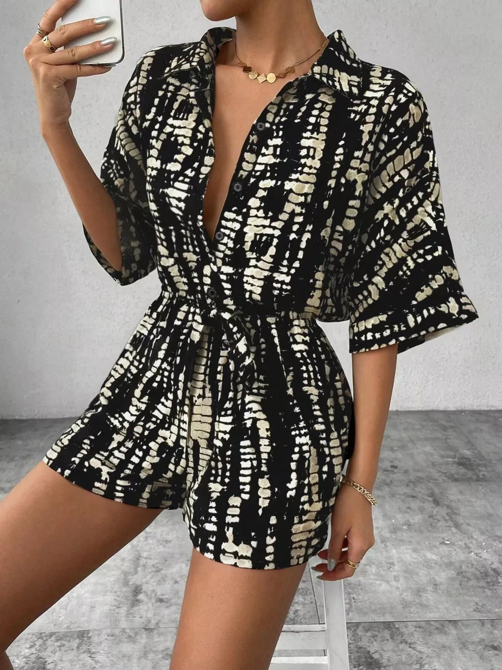 Black and cream tie-dye belted romper with collared button-front and short sleeves.