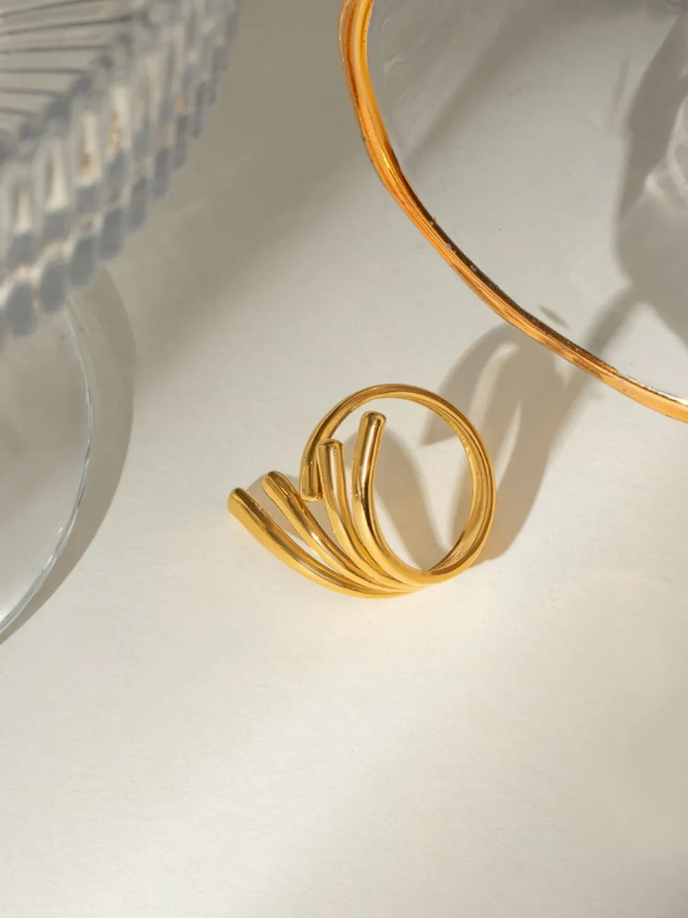 Gold sculptural spiral ring with multiple bands and a modern design.