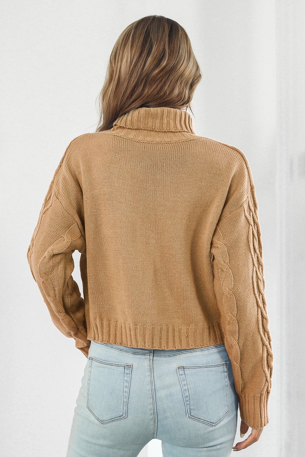 Camel cable knit cropped turtleneck sweater with braided sleeves.