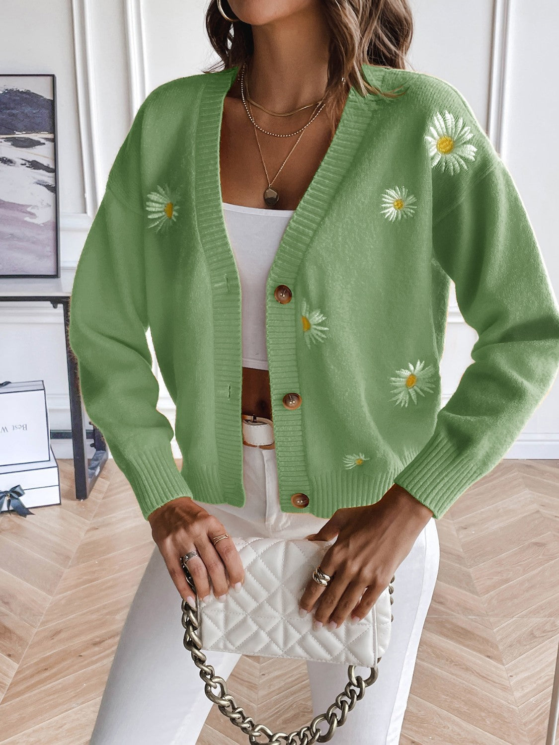 Matcha green button-down cardigan with embroidered daisies and button closure.