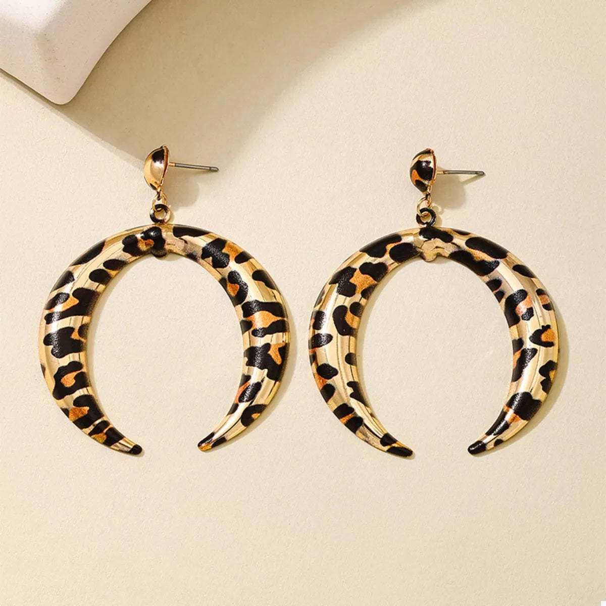 Gold crescent dangle earrings with leopard print pattern