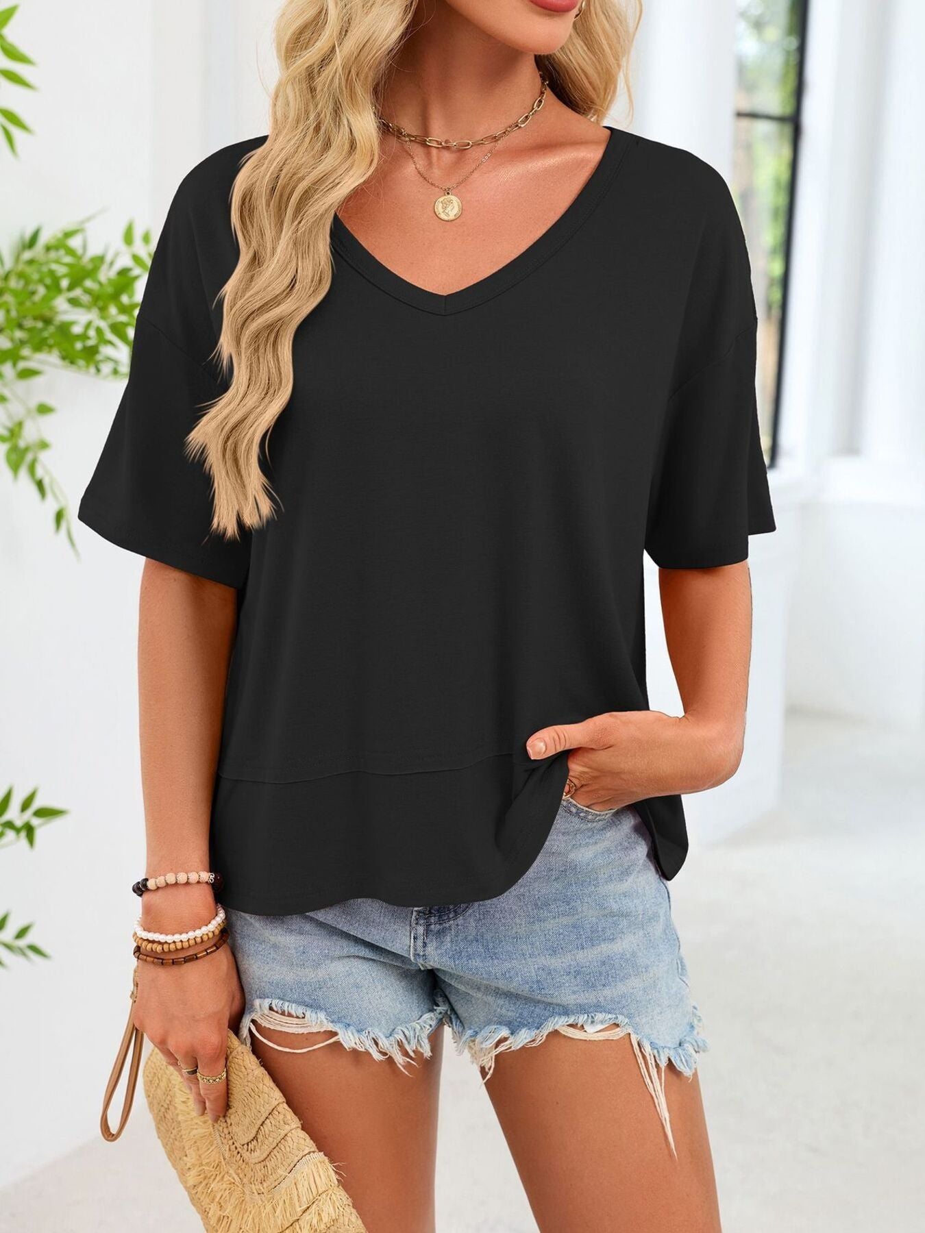 Black relaxed fit v-neck t-shirt with short sleeves and a layered hem detail.