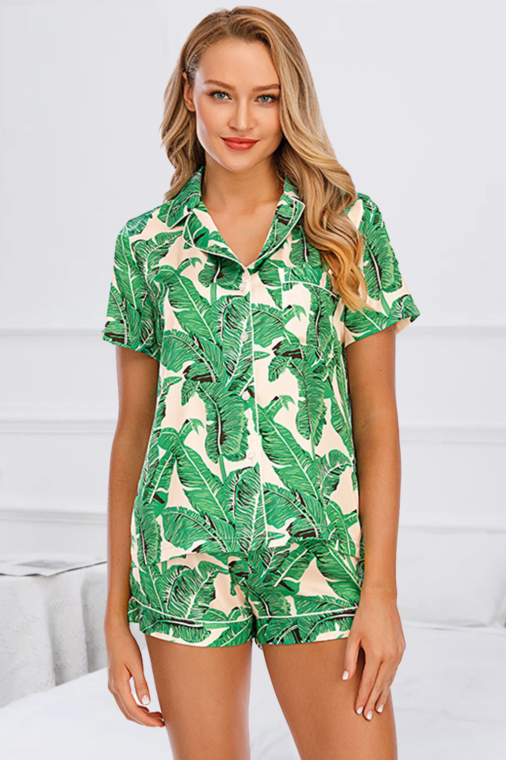 Green botanical print satin pajama set with button-up shirt and shorts.