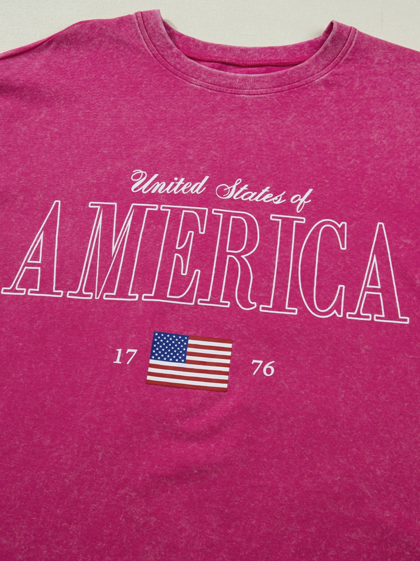 Patriotic graphic cotton t-shirt in pink with "United States of America" text and US flag graphic.