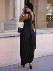 Black scoop neck maxi dress with draped fabric and a side slit, worn by a model.