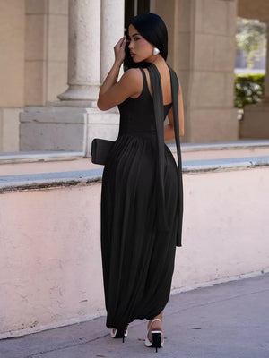 Black scoop neck maxi dress with draped fabric and a side slit, worn by a model.