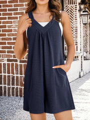 Dark blue textured gathered-yoke romper with pockets and V-neck.