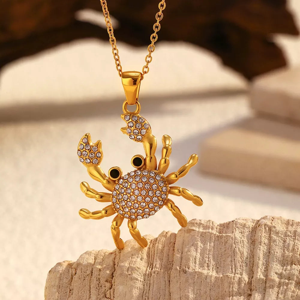 Gold-plated crab pendant necklace with clear crystals and black eyes on a delicate chain.