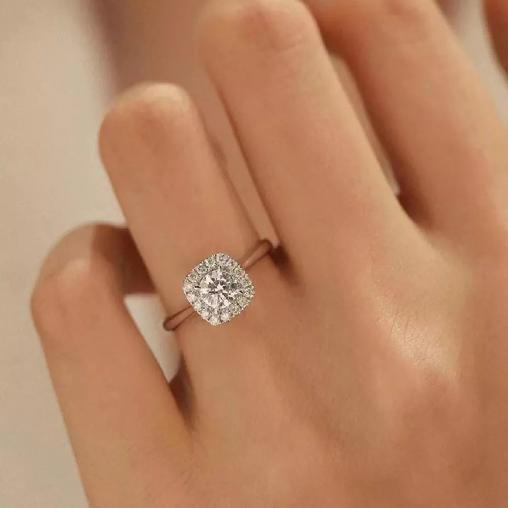 Elegant moissanite and sterling silver ring with cushion-cut center stone and halo.