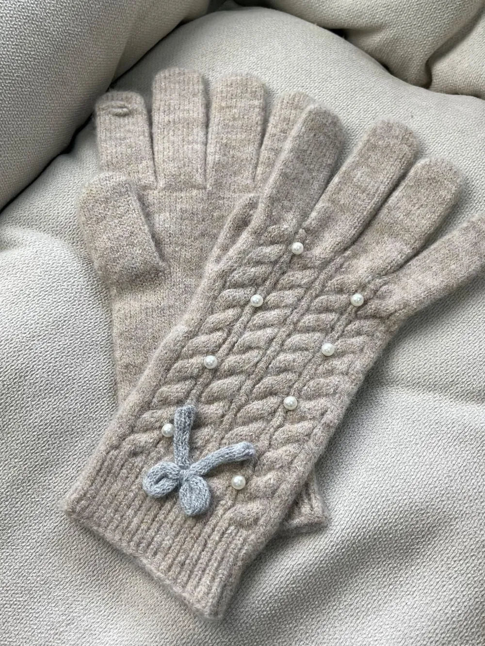Khaki cable knit gloves with pearl embellishments and a bow detail.