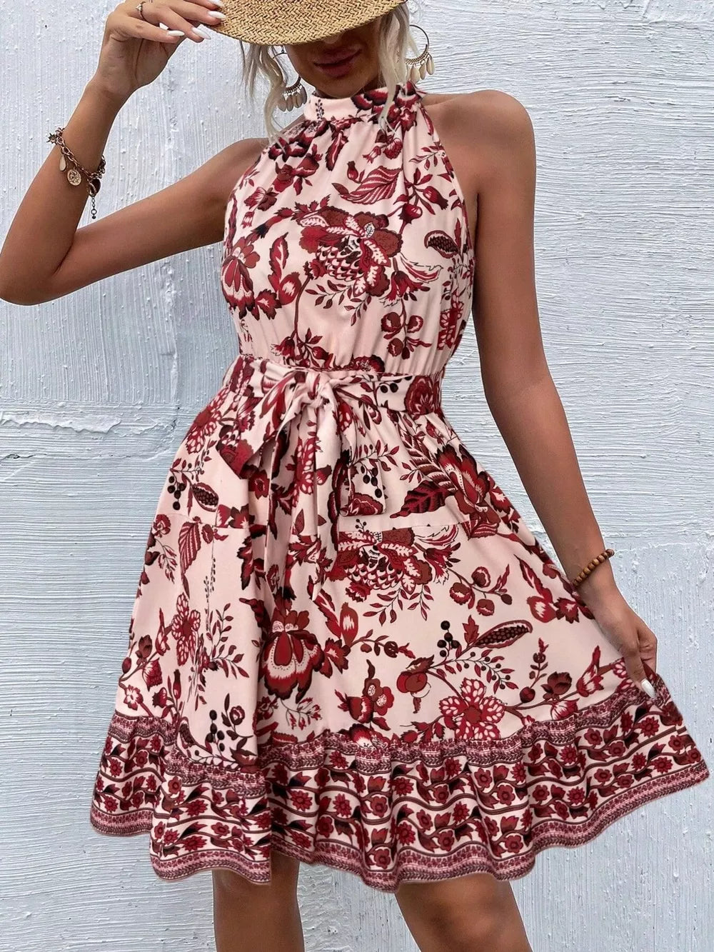 Floral print halter dress in burnt coral with tie waist and ruffled hem.