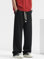 Men's black casual drawstring sweatpants with embroidered logo detail.