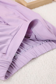 Draped wrap top and pleated trousers set in soft purple with elastic waistband detail.
