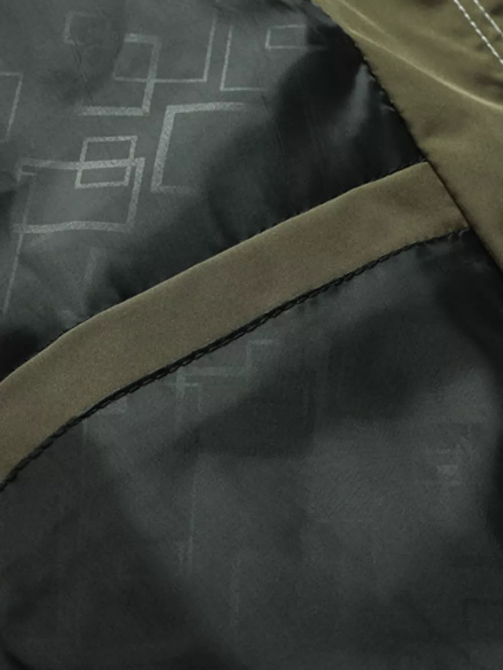Green hooded jacket interior detail with geometric pattern lining and pocket trim.