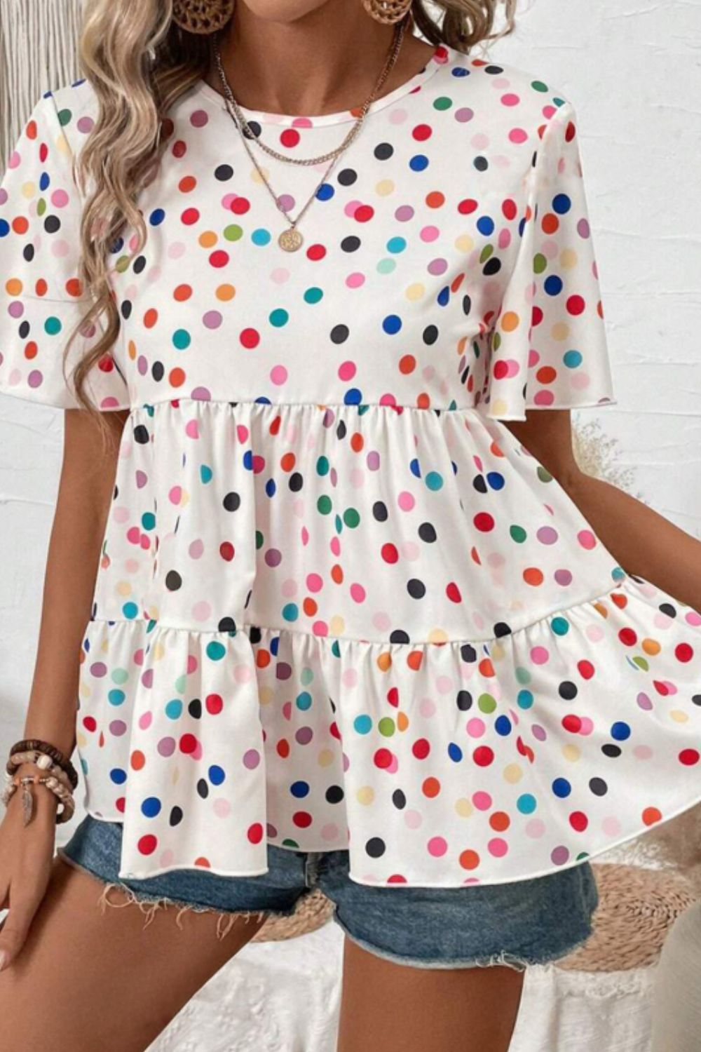 White tiered babydoll blouse with rainbow polka dots and flutter sleeves.